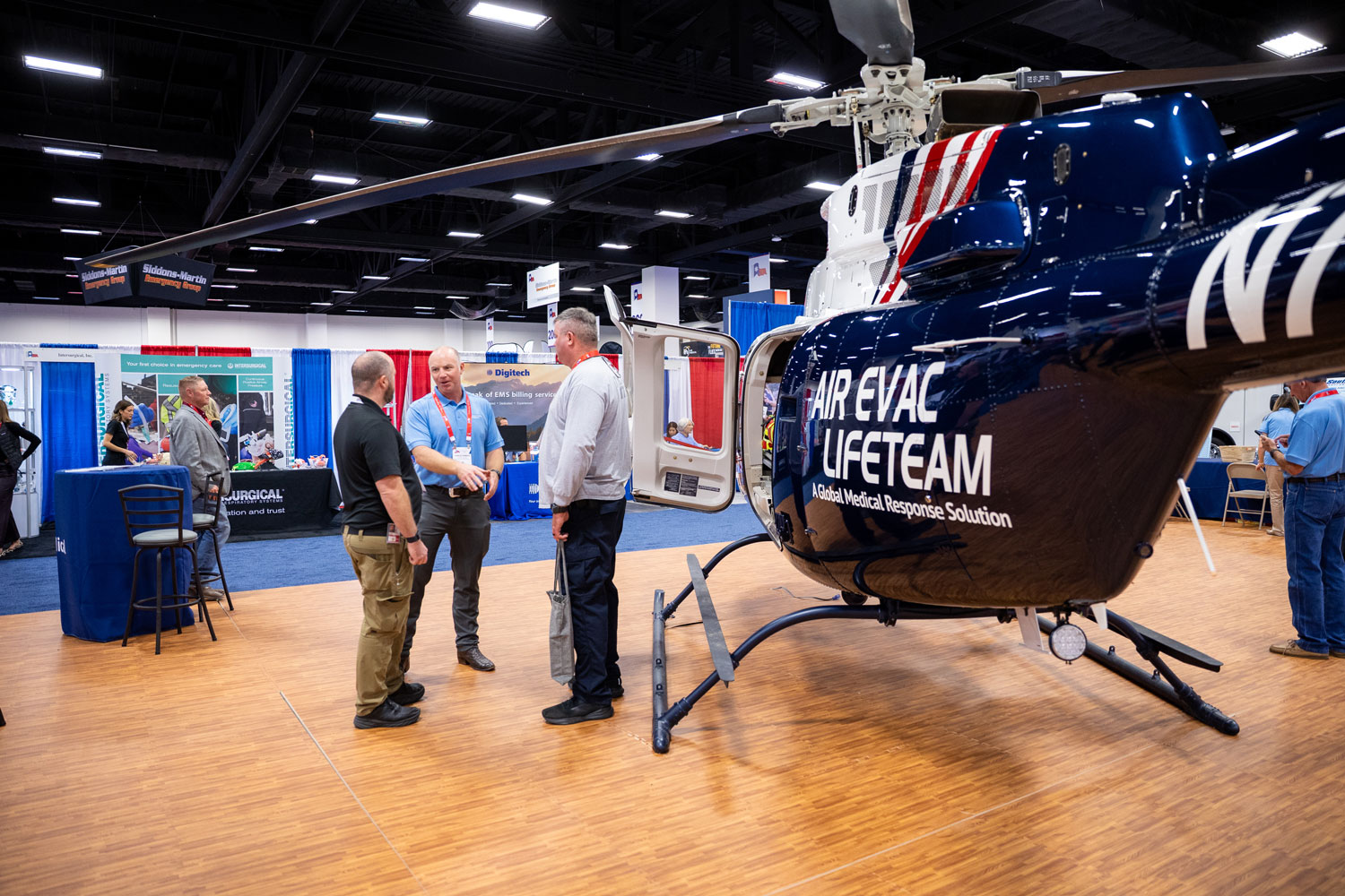 Exhibitors speaking with attendees in booth with helicopter nearby | Texas EMS Conference